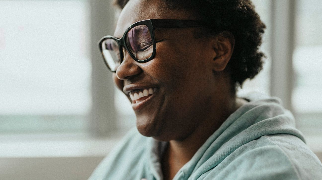 Female sitting by a window smiling and looking relaxed